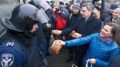 A handout picture released on December 10, 2013 by Ukrainian Union Opposition press services hows US Assistant secretary of State for European and Eurasian Affairs Victoria Nuland (R) distributing cakes to riot policemen on the Independence Square in Kiev on December 10, 2013. (AFP Photo)