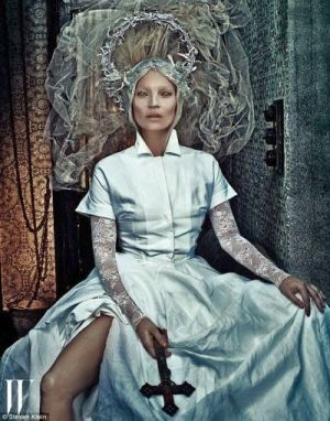 Supermodel Kate Moss looking demonic and posing with an inverted crucifix, whilst dressed as the bride of Christ.