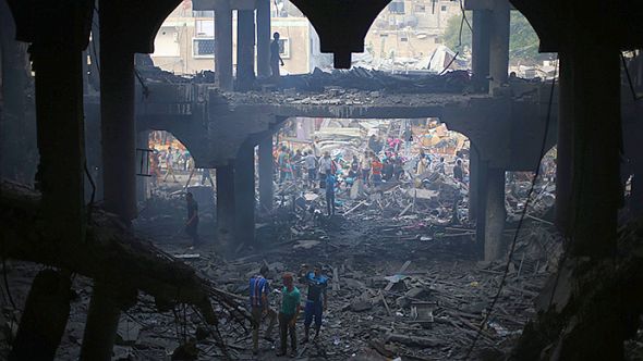 Palestinians look at the remains of a commercial center, which witnesses said was hit by an Israeli air strike on Saturday, in Rafah in the southern Gaza Strip August 24, 2014 (Reuters / Ibraheem Abu Mustafa)
